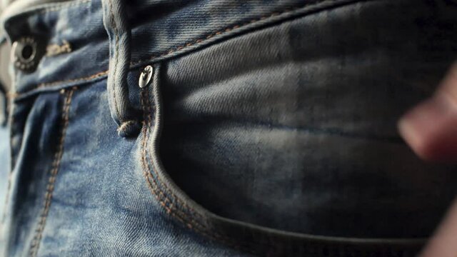 Guy shows how he put fat stack of banknotes, dollars, bucks into his jeans pockets. Demonstration of success and profit rising. Large pile of paper bills money goes in pocket, focused macro shot.