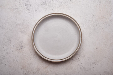 Empty ceramic plate on light concrete table background. Copy space. Menu recipe concept. Top view....