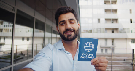 Pov shot of handsome man looking at camera, talking and showing immunity passport