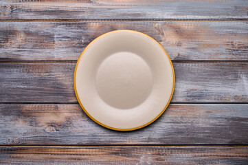 Light empty plate with brown edge on from boards wooden background, top view. Copy space. Menu recipe concept