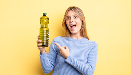 pretty blonde girl looking excited and surprised pointing to the side. olive oil concept
