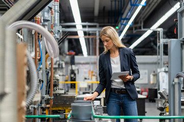 Female manager with digital tablet checking production line in factory