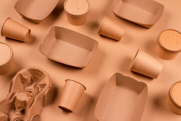 Eco-friendly tableware and kraft paper food packaging on kraft paper background - paper cups, plates and containers. Sustainable food packaging, zero waste packaging concept. Flat lay