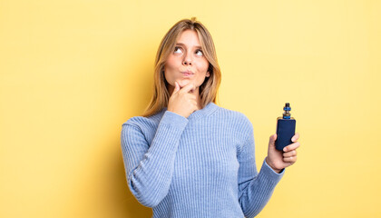 pretty blonde girl thinking, feeling doubtful and confused. smoke vaporizer concept