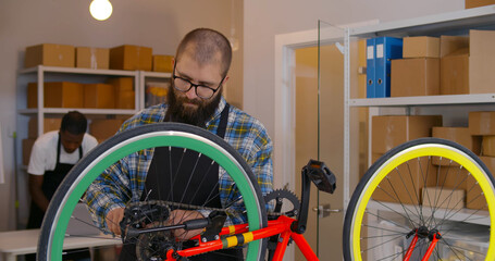 Bike mechanic fixing bicycle wheel in workshop