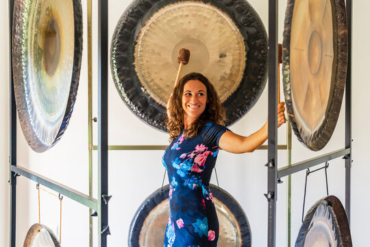 Female professional therapist playing gongs with mallets in studio