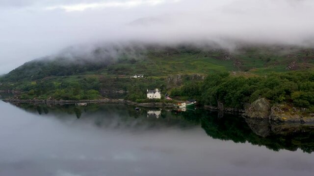 Rotating drone shot of a small home or fish house at Loch Carron, on the west coast of Ross and Cromarty in the Scottish Highlands