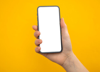 Hand with mobile phone mockup screen on a yellow background, copy space photo