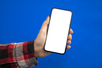 Hand with mobile phone mockup screen on a blue background, copy space photo