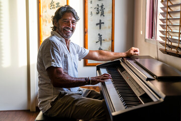 Smiling man playing piano at home