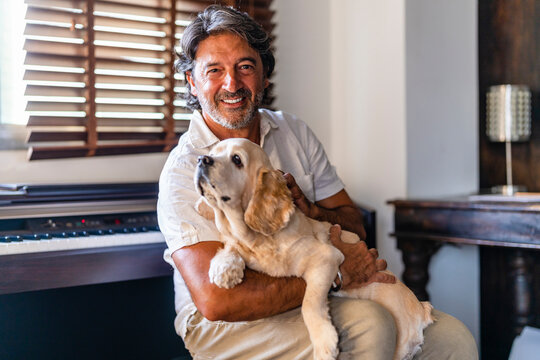 Happy Man Petting Dog While Sitting At Home