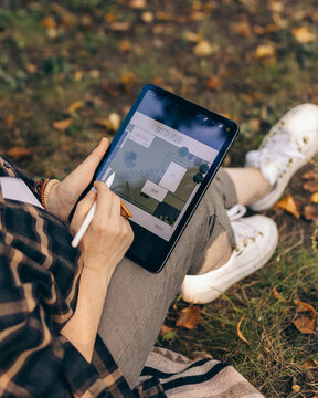person holding digital tablet outdoor, person draws graphic landscape pictures on a tablet