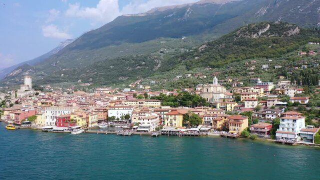 Aerial video view from waterfront of the historic city of Malcesine, the Scaliger Castle in Malcesine, the port and restaurants of old town, Lake Garda, Italy - K4 movie