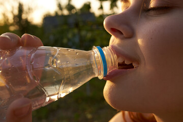 woman drinking water from a bottle face closeup summer