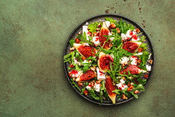 Fig salad with white cheese, walnuts, arugula and jam dressing on rust green background, top view, copy space
