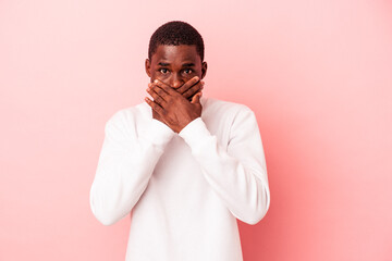 Young African American man isolated on pink background covering mouth with hands looking worried.