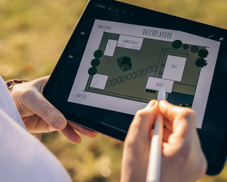 hand holding digital tablet, person draws graphic landscape pictures on a tablet