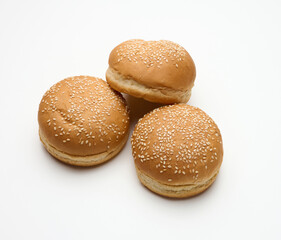 baked round fresh white wheat flour bun sprinkled with sesame seeds on a white table. Hamburger, cheeseberger and sandwich bun