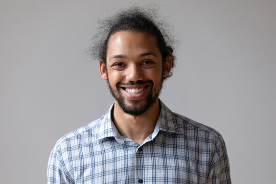 Head shot portrait smiling African American young man isolated on grey studio wall background, happy bearded male looking at camera, excited businessman or student posing for profile picture