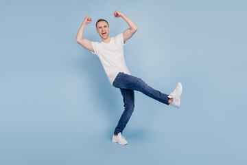 Fototapeta na wymiar Full size photo of young cheerful man happy positive smile celebrate win victory lucky lottery fists hands isolated over blue color background
