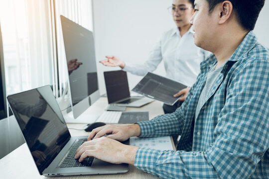 Two software developers are analyzing together about the code written into the program on the computer in office room.