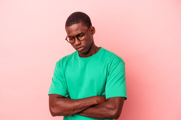 Young African American man isolated on pink background frowning face in displeasure, keeps arms...