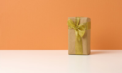 brown gift box on white table, orange background, surprise and gift