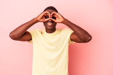 Young African American man isolated on pink background showing okay sign over eyes