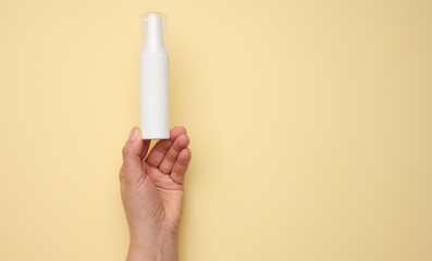 female hand holding white plastic bottle. Packaging for cream, gel, serum, advertising and product promotion