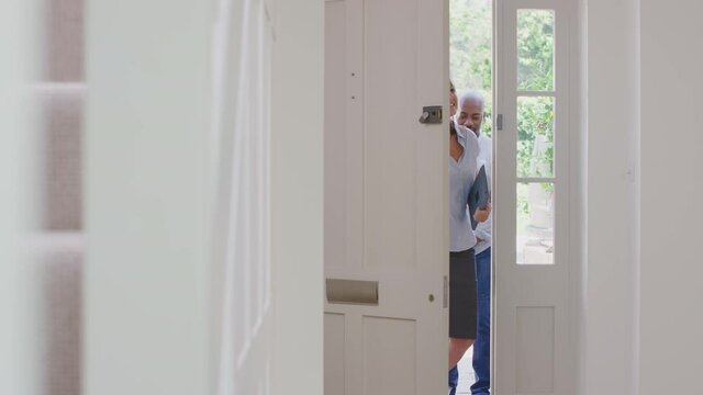Female realtor opening front door and showing couple around inside of potential new house or apartment - shot in slow motion