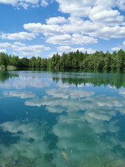 Fototapeta premium The shore of the lake is bright with clear water, in which you can see the marble on the bottom and reflect the sky with clouds, in the mountain park Ruskeala.