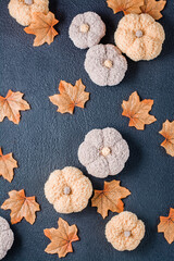 Handcraft autumn still life - knitted pumpkins and maple fabric leaves on a black background. Halloween and Thanksgiving decor. Vertical and top view