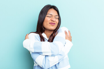 Young Venezuelan woman isolated on blue background hugs, smiling carefree and happy.