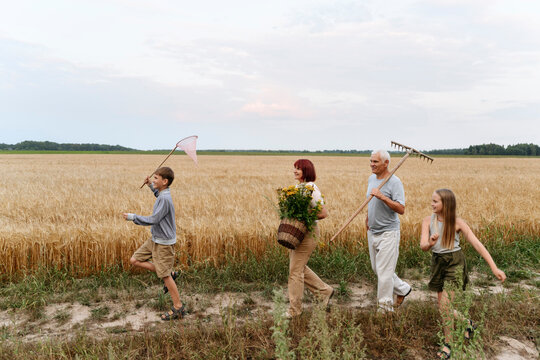 Playful children walking with grandparents on field