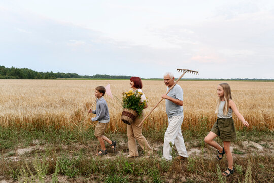 Family with tansy flowers and rake walking on field