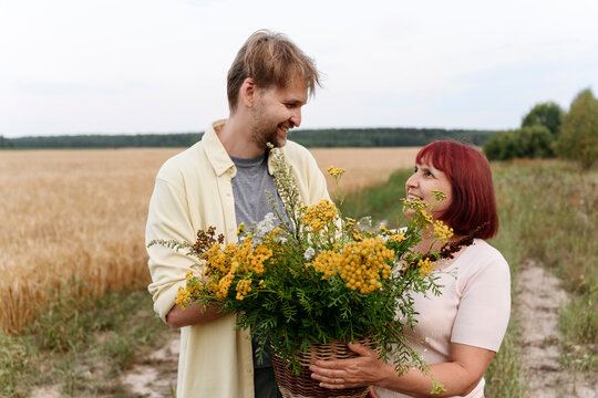 Smiling man holding basket of tansy flowers with mother