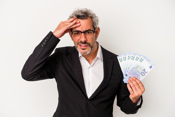 Middle age business man holding bills isolated on blue background  being shocked, she has remembered important meeting.