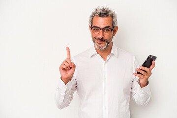 Middle age caucasian business man holding a mobile phone isolated on white background showing number one with finger.