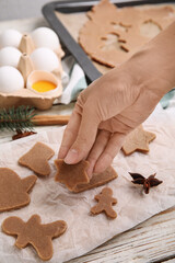 Woman making gingerbread Christmas cookies at white wooden table, closeup