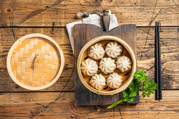 Momo dumplings in a bamboo steamer. Wooden background. Top view - obrazy, fototapety, plakaty