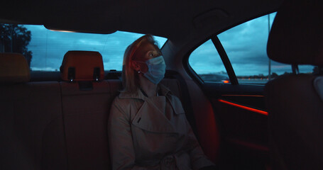 Portrait of woman wearing medical sterile mask in taxi car on backseat