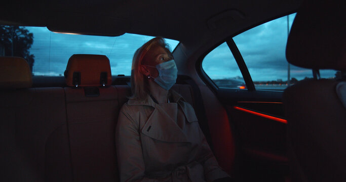 Portrait Of Woman Wearing Medical Sterile Mask In Taxi Car On Backseat