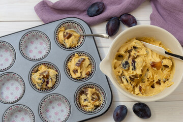 muffin tray partly filled with paper cups and bowl with dough