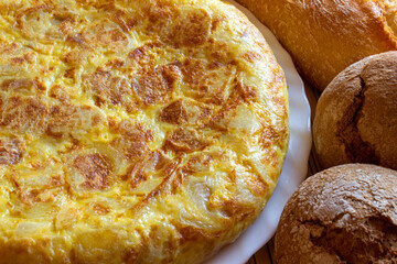 Primer plano de una tortilla de patatas, receta típica procedente de España, acompañada de pan