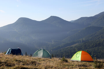 Picturesque mountain landscape with camping tents in morning