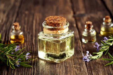 A bottle of rosemary essential oil with fresh rosemary