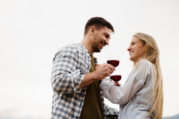 Smiling couple toasting wine glasses outdoors in mountains