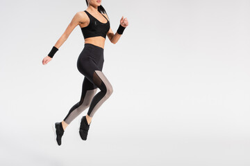 Fototapeta na wymiar partial view of young woman in sportswear levitating on grey