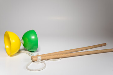 Diábolo de plástico amarillo y verde con dos palos de madera y una cuerda blanca listo para hacer...