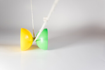 Diábolo de plástico amarillo y verde con una cuerda blanca listo para hacer malabares sobre un...